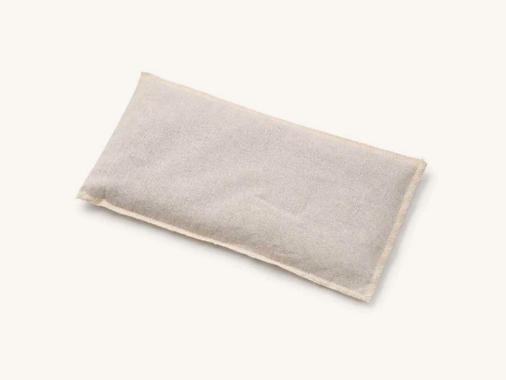 Almohadita de tela beige con borde a la vista.